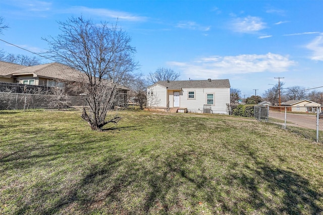 back of property with a lawn and fence