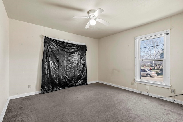 carpeted spare room with ceiling fan and baseboards