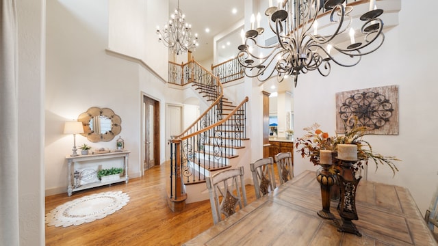 dining space with baseboards, stairway, wood finished floors, a high ceiling, and a chandelier