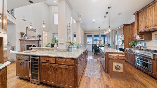 kitchen featuring beverage cooler, appliances with stainless steel finishes, a spacious island, and decorative light fixtures