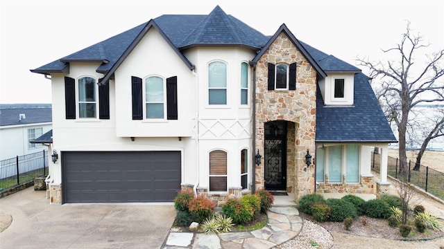 french provincial home featuring driveway, a garage, fence, and stucco siding