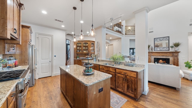 kitchen featuring visible vents, a kitchen island, open floor plan, hanging light fixtures, and stainless steel appliances