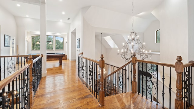 corridor with an upstairs landing, light wood-type flooring, an inviting chandelier, and recessed lighting