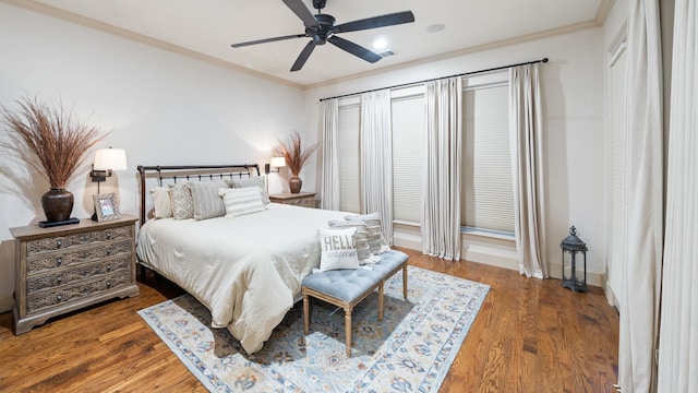 bedroom featuring a ceiling fan, dark wood finished floors, crown molding, and baseboards