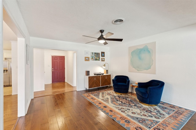 living area with wood-type flooring, visible vents, and a textured ceiling