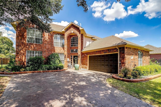 view of front of property featuring a garage, roof with shingles, driveway, and brick siding