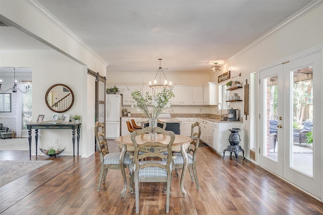 dining area with a chandelier, wood finished floors, french doors, and a barn door