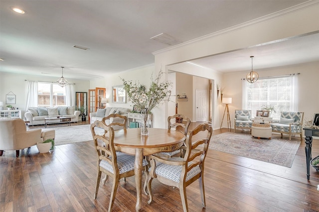 dining space featuring crown molding, hardwood / wood-style floors, visible vents, and an inviting chandelier