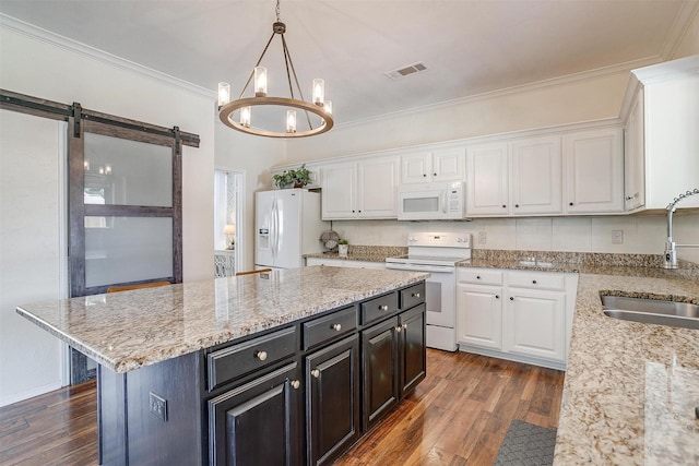 kitchen featuring white appliances, white cabinets, a kitchen island, dark cabinetry, and a sink