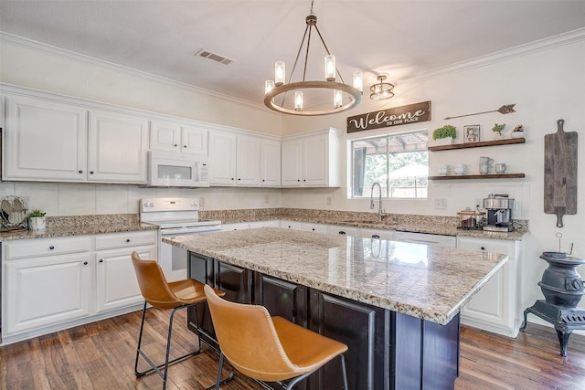 kitchen featuring white appliances, white cabinets, dark wood-style floors, ornamental molding, and a center island