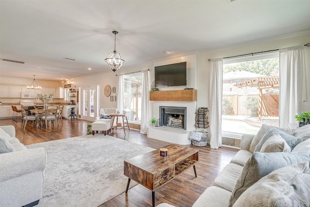 living room with a chandelier, wood finished floors, and a tile fireplace