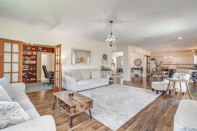 living area with a chandelier, wood finished floors, and ornamental molding