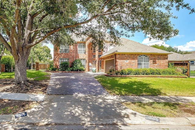 traditional home featuring brick siding, concrete driveway, a front yard, fence, and a garage