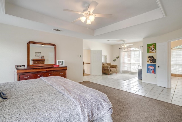 bedroom featuring light tile patterned floors, a tray ceiling, visible vents, and light colored carpet