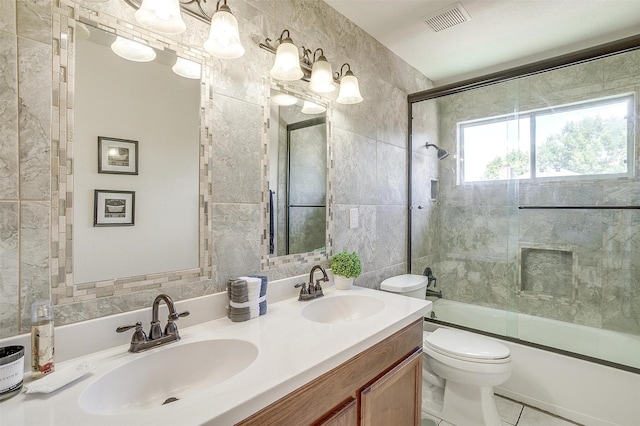 bathroom with shower / bath combination with glass door, a sink, visible vents, and tile walls