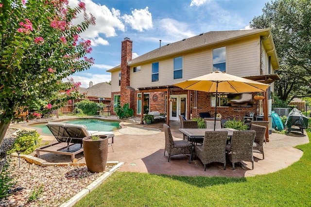 rear view of house with a fenced in pool, french doors, brick siding, a chimney, and fence