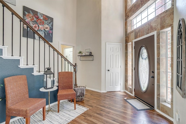 entrance foyer featuring stairway, wood finished floors, a towering ceiling, and baseboards