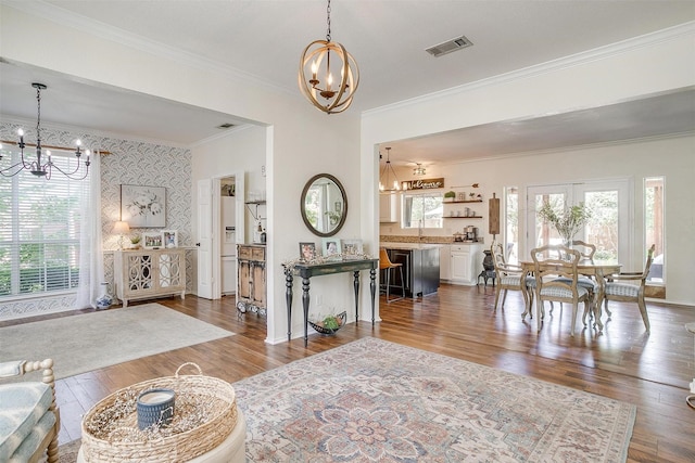 dining space with wood finished floors, visible vents, crown molding, and an inviting chandelier