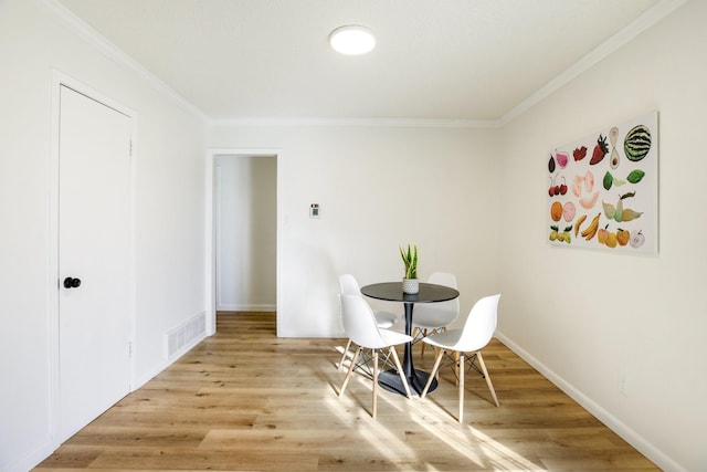 dining room featuring light wood-style floors, baseboards, and ornamental molding