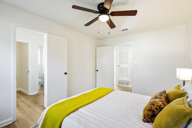 bedroom with baseboards, connected bathroom, visible vents, and light wood-style floors