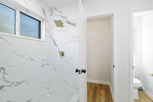 full bathroom featuring wood finished floors, a marble finish shower, toilet, and baseboards