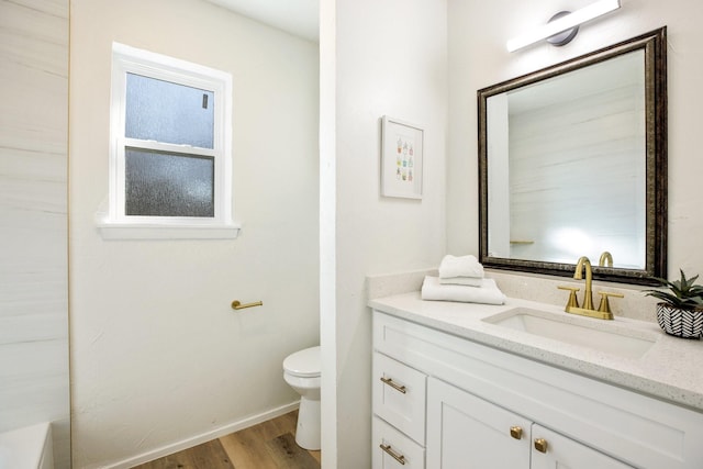 full bath featuring toilet, baseboards, wood finished floors, and vanity