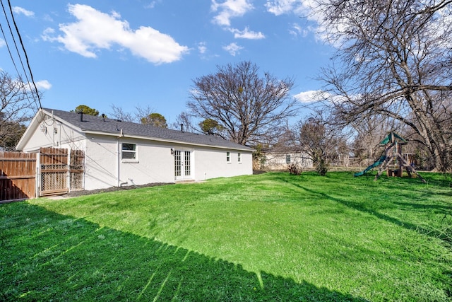 view of yard featuring french doors, a playground, and fence