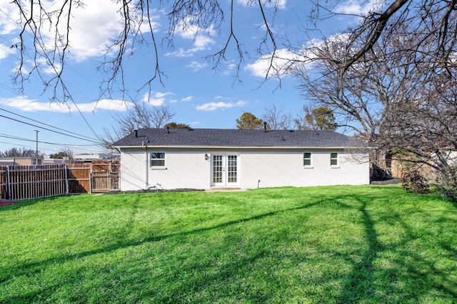 rear view of property featuring french doors, a lawn, fence, and stucco siding