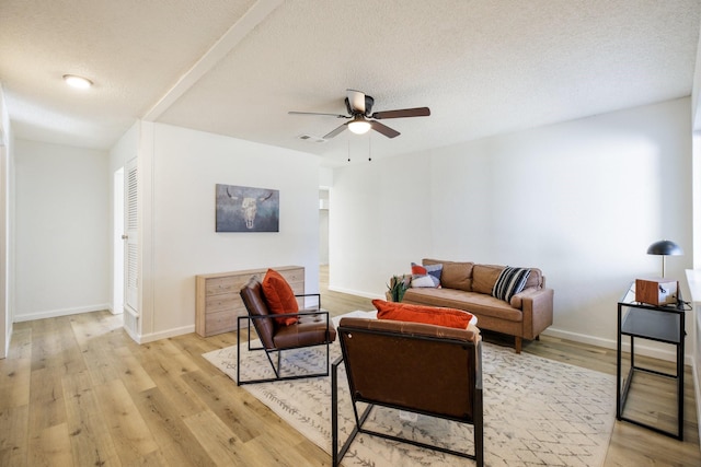 living area featuring light wood-style floors, ceiling fan, a textured ceiling, and baseboards