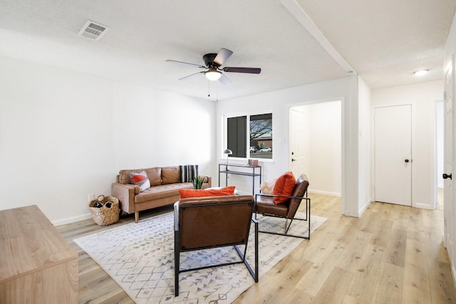 living area with visible vents, light wood-style floors, a ceiling fan, a textured ceiling, and baseboards