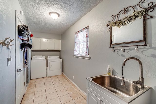 laundry room featuring cabinet space, independent washer and dryer, a textured ceiling, a sink, and light tile patterned flooring