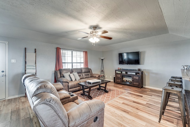 living area featuring ceiling fan, baseboards, and wood finished floors