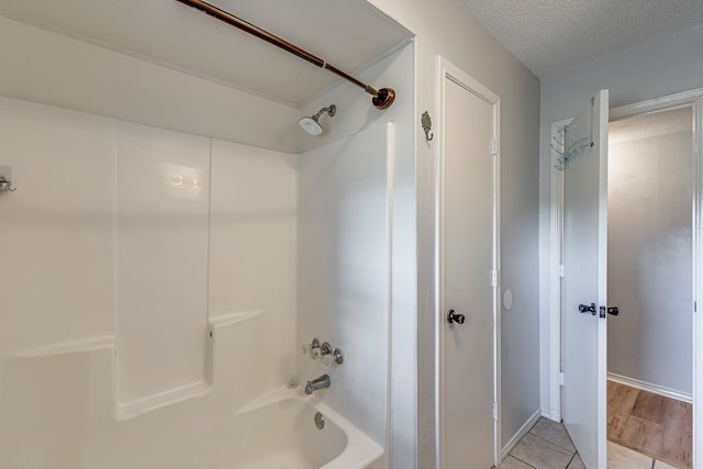 full bath featuring tub / shower combination, a textured ceiling, and tile patterned floors