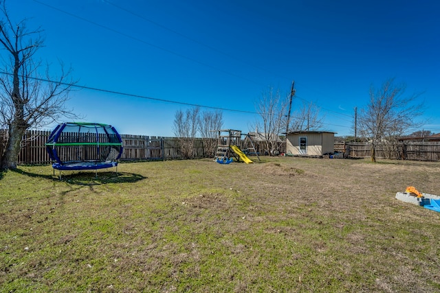 view of yard with a trampoline, a playground, a fenced backyard, and an outdoor structure