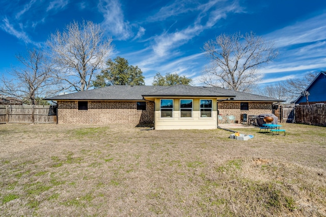 rear view of property with a yard, brick siding, and a fenced backyard