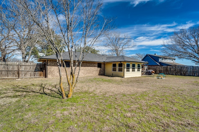 back of house with a yard, brick siding, and a fenced backyard