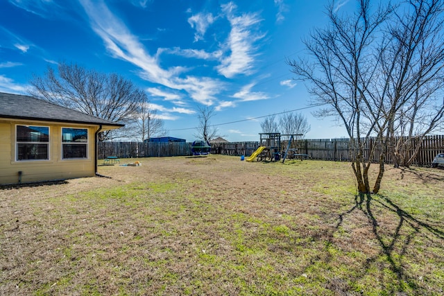 view of yard with a fenced backyard, a trampoline, and a playground