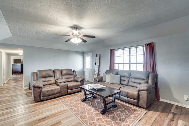 living area with a ceiling fan, a textured ceiling, baseboards, and wood finished floors