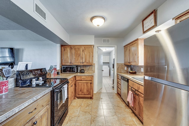 kitchen featuring visible vents, appliances with stainless steel finishes, washer / clothes dryer, and tile counters