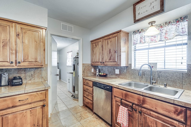 kitchen with brown cabinets, visible vents, dishwasher, and a sink