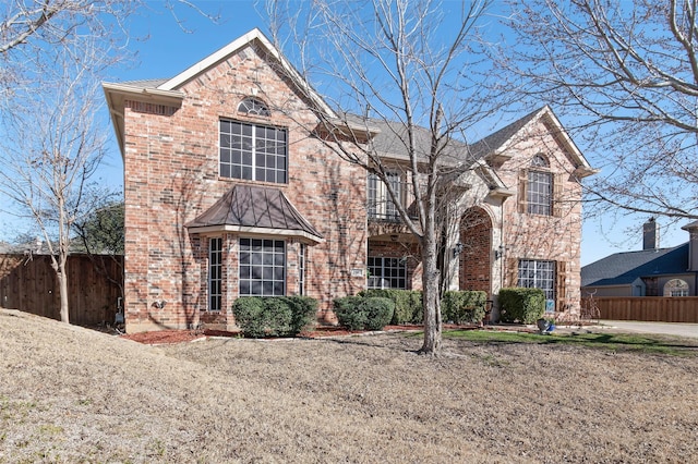 traditional-style home with a front yard, fence, and brick siding