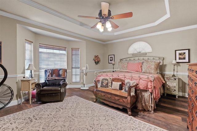 bedroom with dark wood-style floors, a tray ceiling, crown molding, ceiling fan, and baseboards