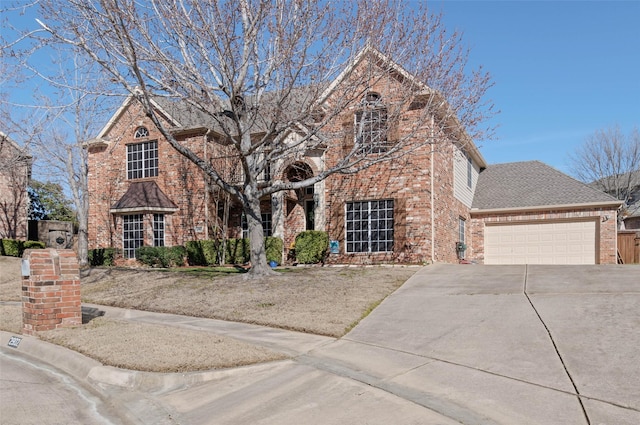 traditional home featuring a garage, driveway, brick siding, and a shingled roof