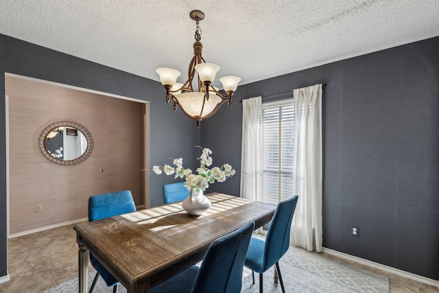 dining room featuring a chandelier, a textured ceiling, and baseboards