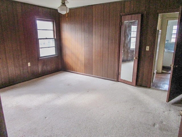 unfurnished room with wood walls and carpet flooring