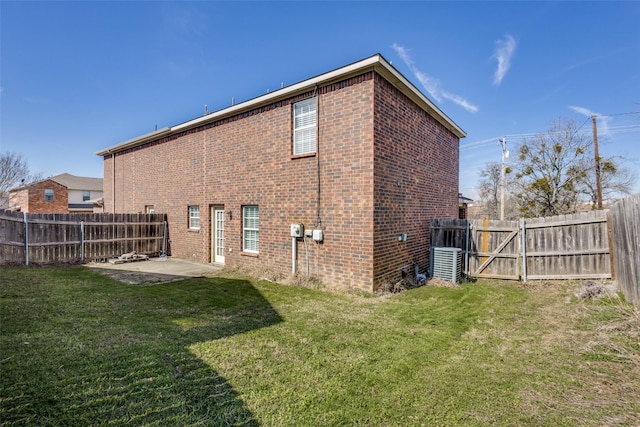 back of property featuring a yard, brick siding, a patio, and a fenced backyard