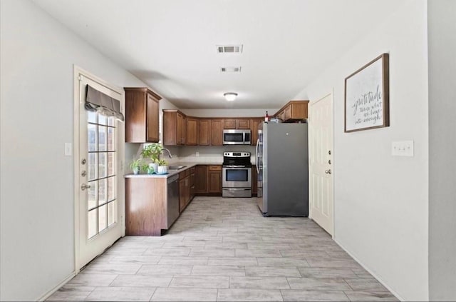 kitchen featuring a sink, stainless steel appliances, light countertops, and visible vents