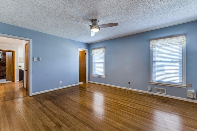 unfurnished room featuring a ceiling fan, visible vents, baseboards, and wood finished floors