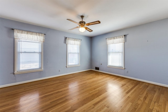 spare room with a ceiling fan, light wood-style flooring, and baseboards