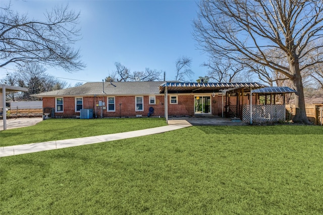 view of front of home featuring brick siding, a front lawn, a patio area, and fence